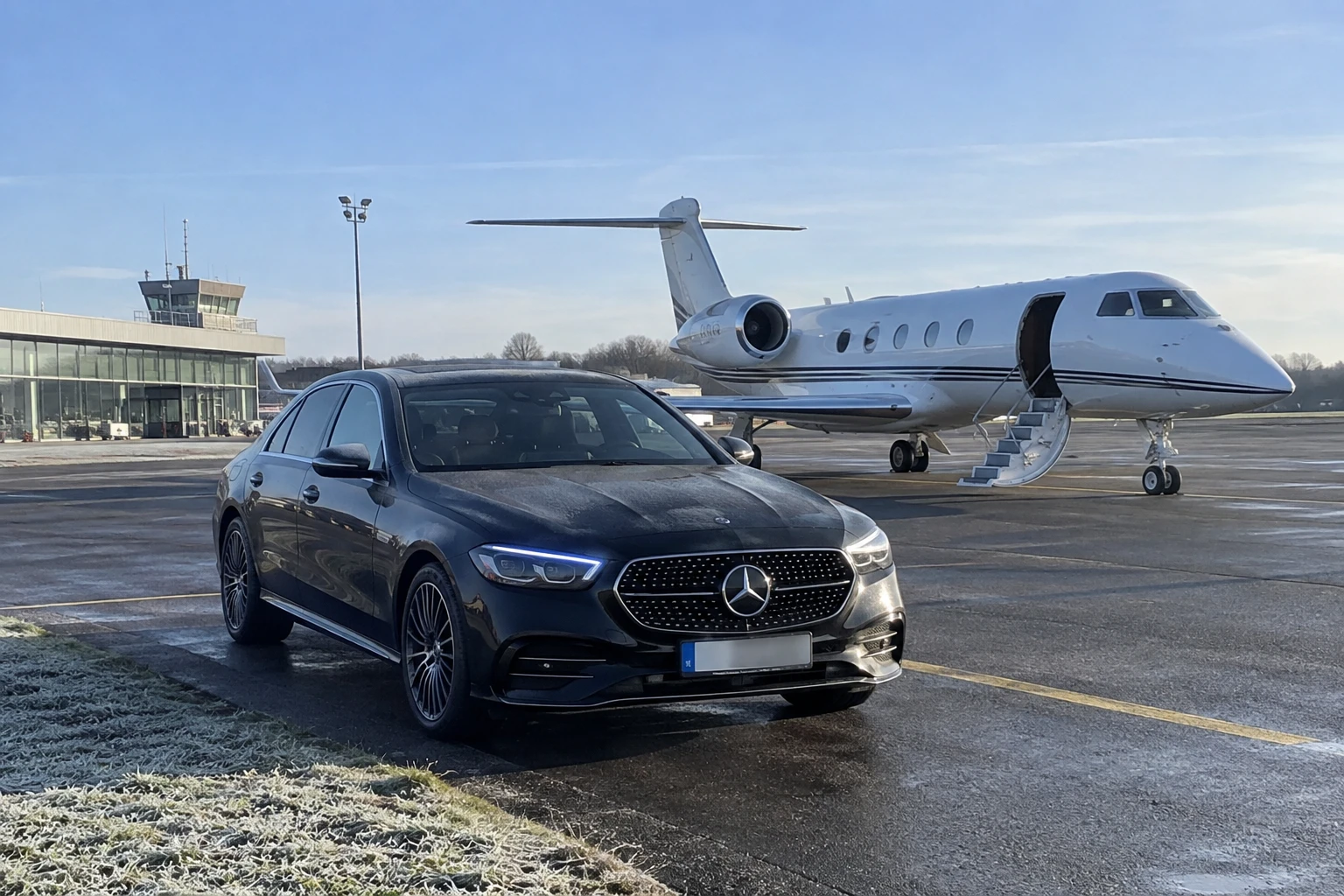 Mercedes Classe E noire sur le tarmac de l'aéroport d'affaires de Lyon-Bron, jet privé porte ouverte en arrière-plan un matin d'hiver