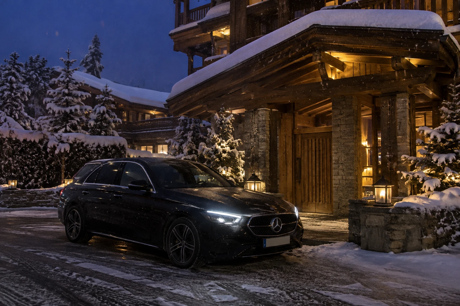 Mercedes Classe E noire devant l'entrée éclairée d'un chalet de luxe à Courchevel 1850, à la tombée de la nuit sous la neige
