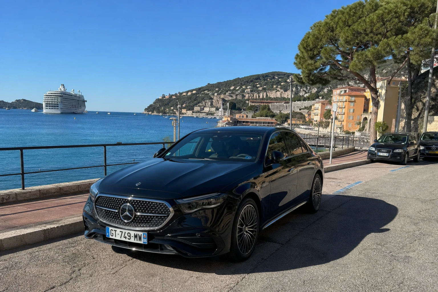 Mercedes Classe E noire garée sur le quai de Villefranche-sur-Mer, paquebot de croisière ancré dans la rade, chauffeur privé pour excursion privée pendant une escale croisière